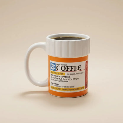 A white ceramic coffee mug with a handle, filled with black coffee, featuring a retro orange and white label styled like a prescription bottle. The mug is set against a solid, warm beige background.
